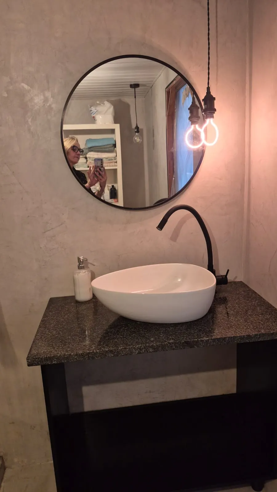 Vessel basin on granite vanity with round mirror and pendant bulb